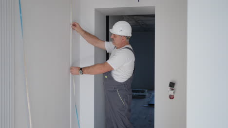 An-electrician-in-a-helmet-installs-and-checks-LED-strips-for-illumination-in-the-apartment.-Turn-on-and-check-the-light-and-decorative-lights
